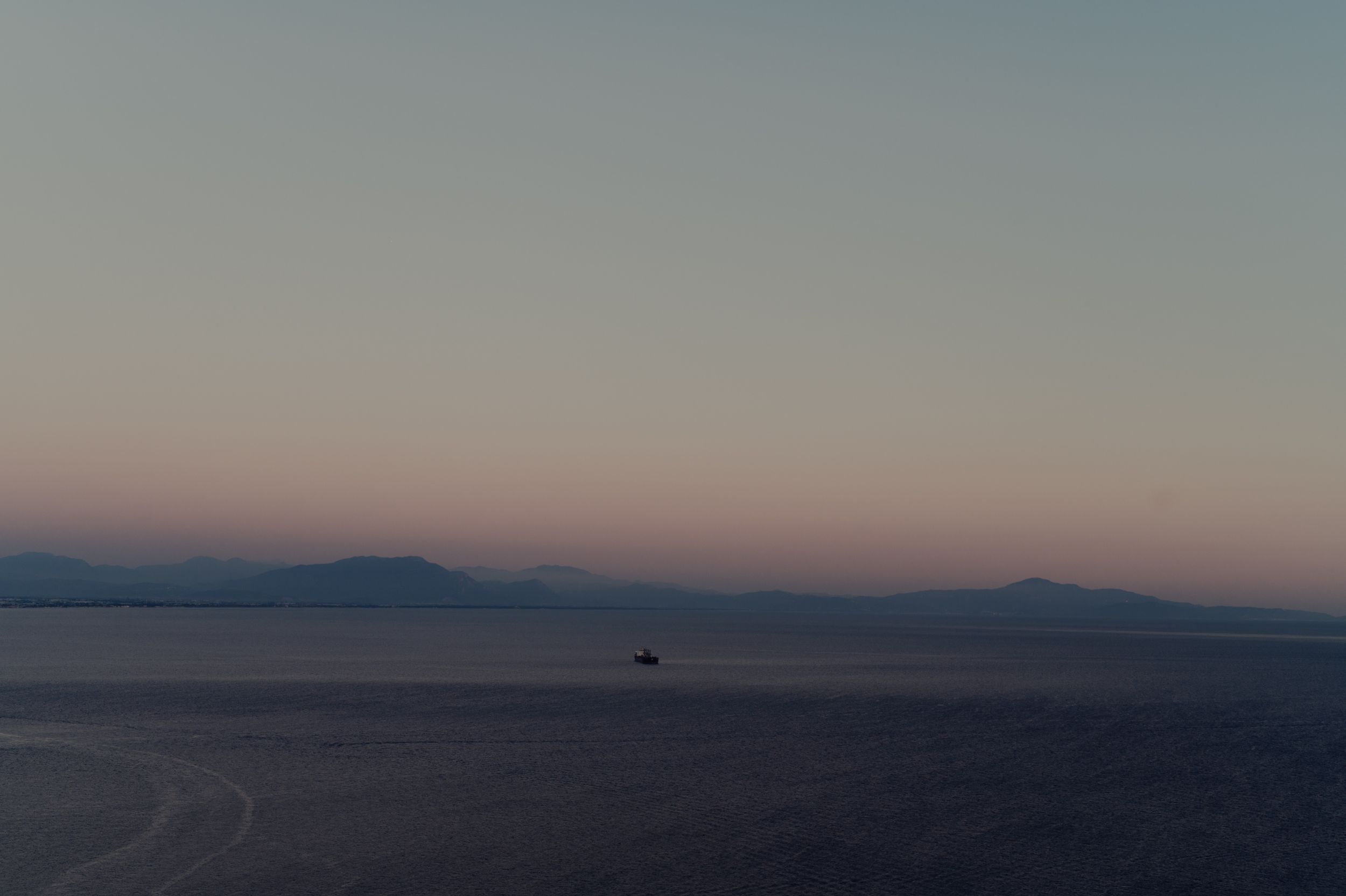 A minimalist landscape showing mountains in soft evening light with hazy atmosphere.
