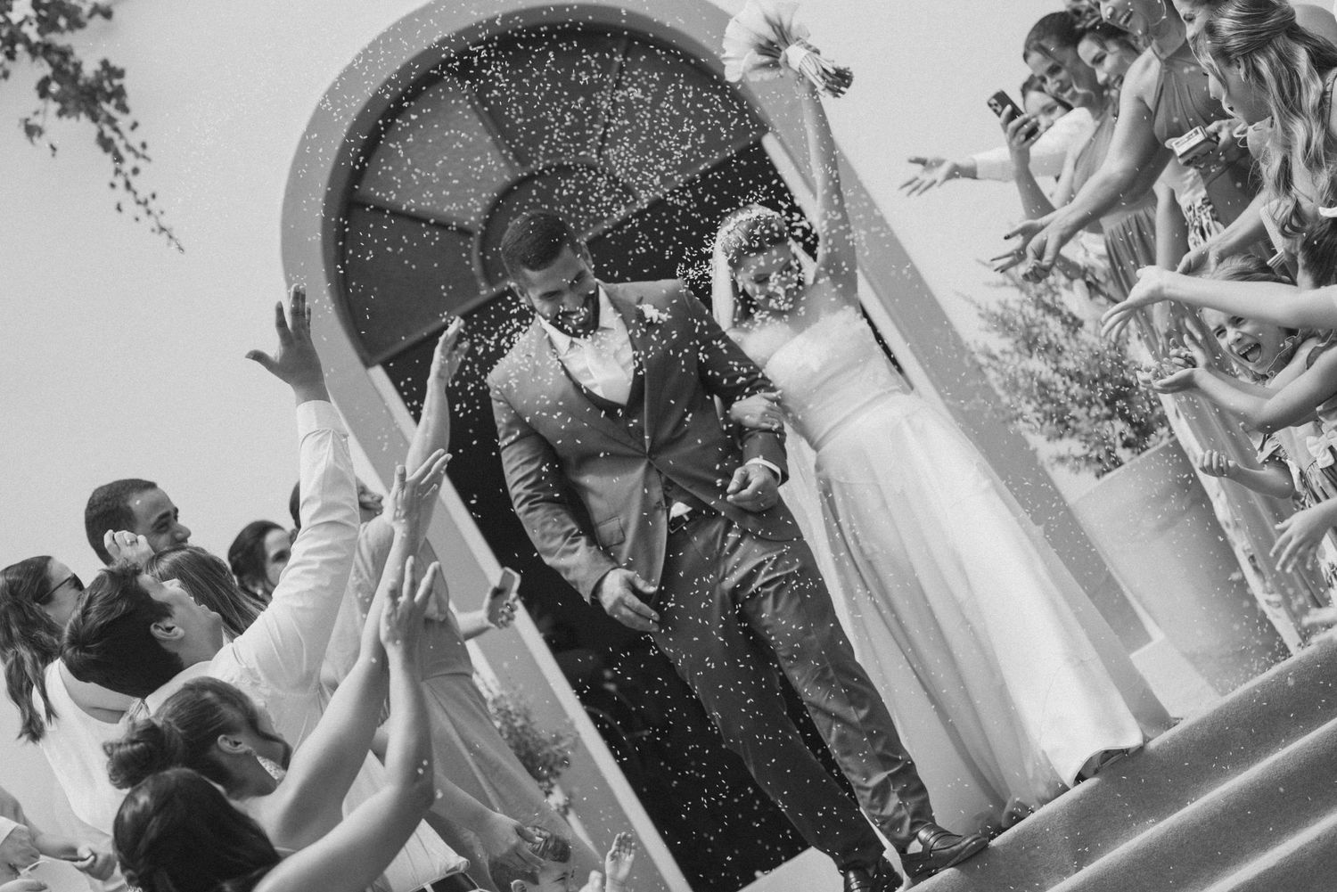 Black and white photo of a wedding ceremony celebration under an ornate archway.