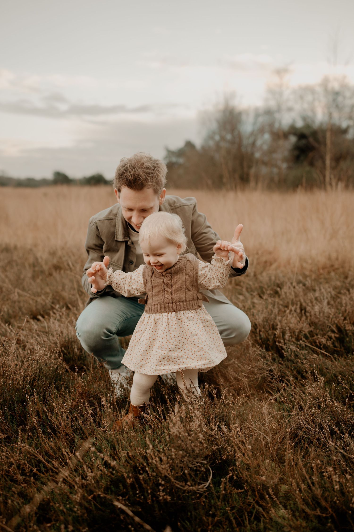 A candid moment in a golden field at sunset as two people share a tender moment among the tall grass.