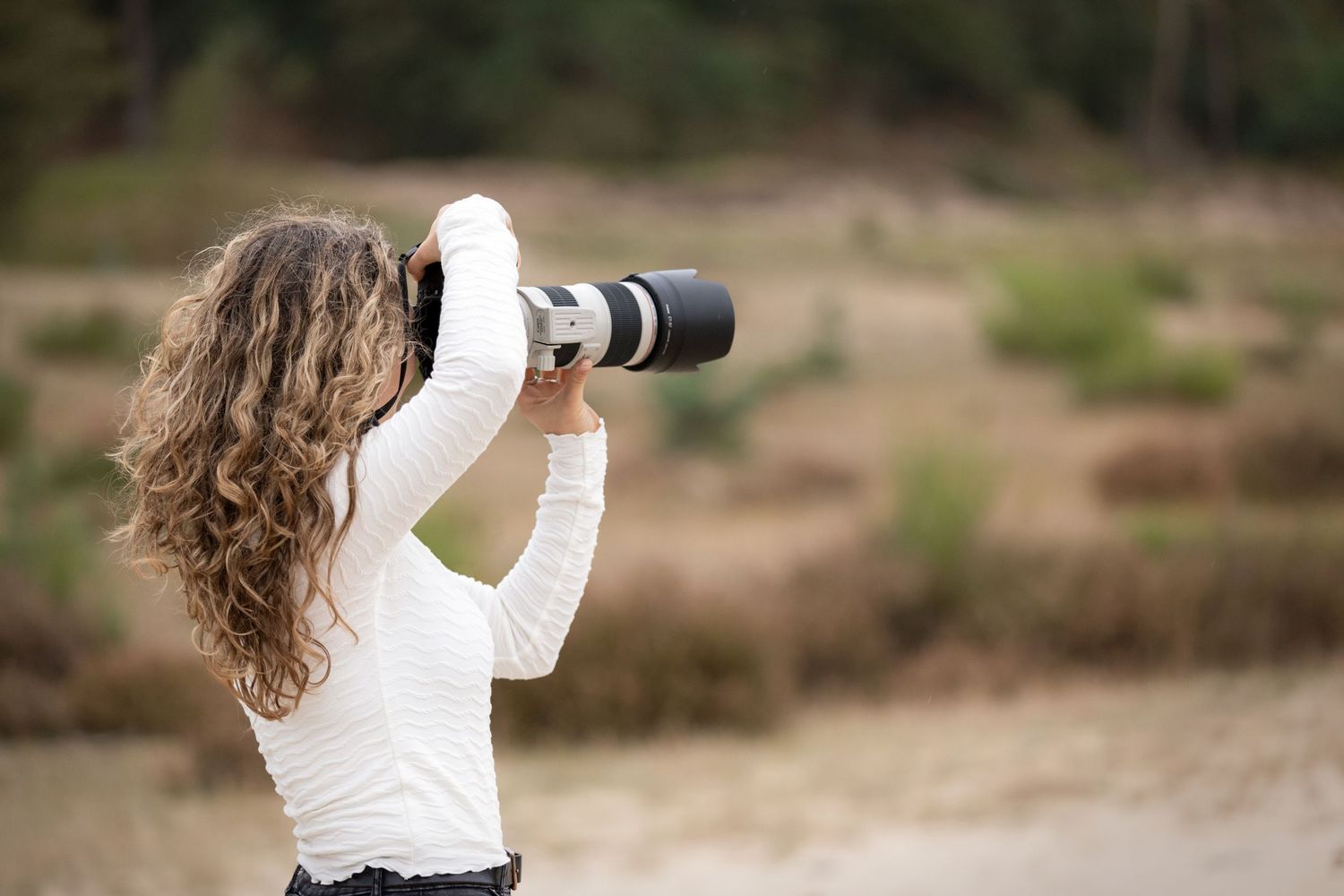 Photographer with camera photographing a horse against a natural outdoor backdrop.