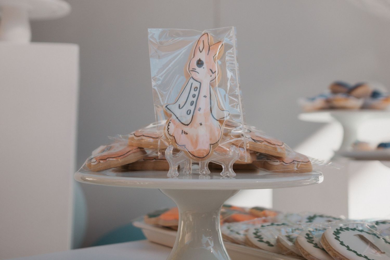 A Peter Rabbit themed cookie displayed on a white cake stand.