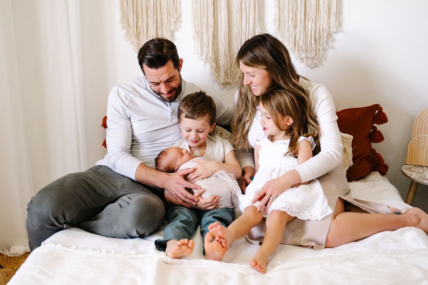 A joyful family lounging together on a bed with bohemian decor in the background.