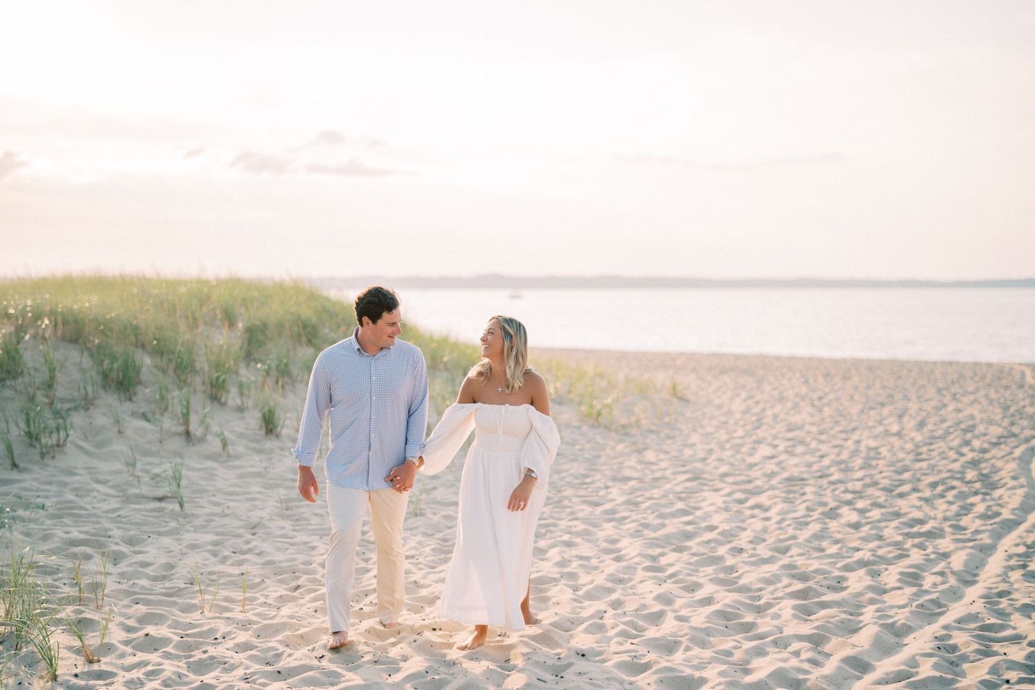 Two people playing on a sandy beach near Mission Point Lighthouse in Northern Michigan on a sunny summer day.