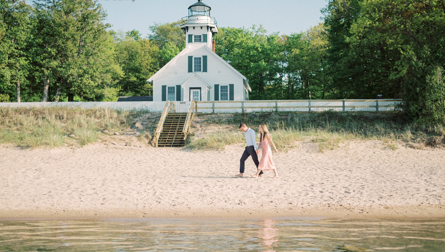 Two people playing on a sandy beach near Mission Point Lighthouse in Northern Michigan on a sunny summer day.