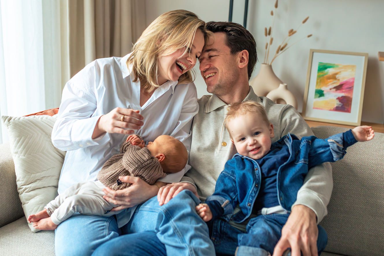 newborn shoot met baby liggend in de armen van mama, samen met papa en een grote peuter broer, thuis ontspannen en gezellig