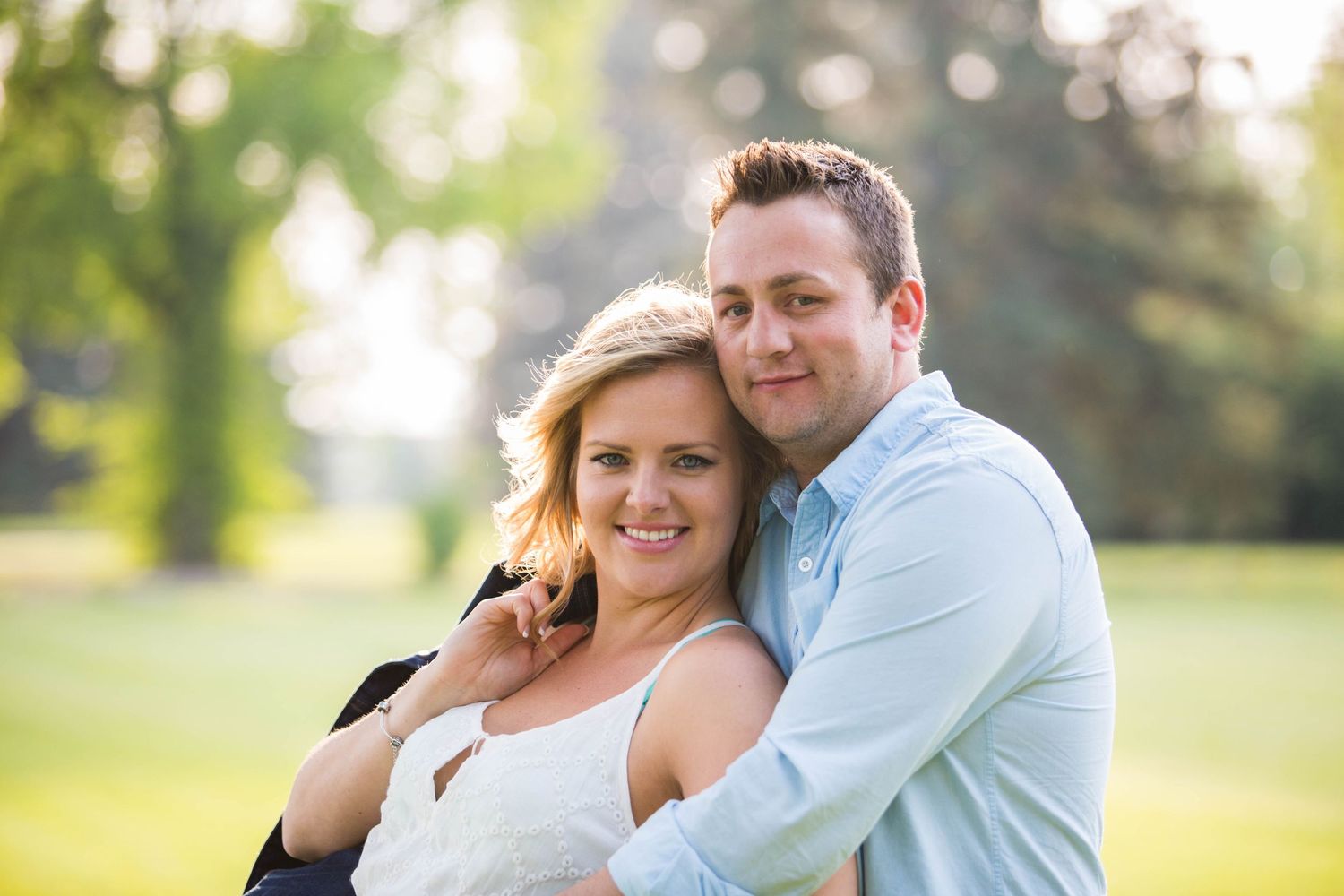 A couple embraces during an outdoor photo session in natural lighting.