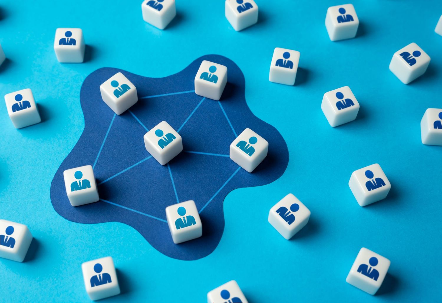 Small white cubes with blue user profile icons scattered on a blue background creating a social network pattern.