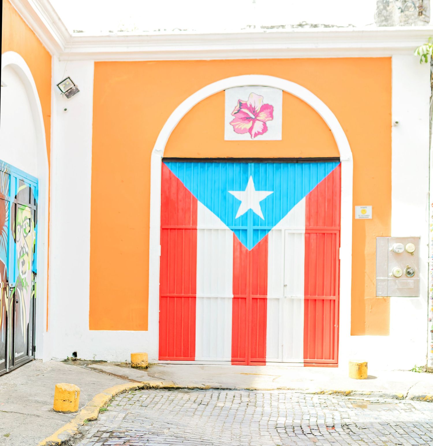 Puerto Rican flag painted on a doorway with an arched entrance in vibrant orange and turquoise surroundings in Old San Juan for photography