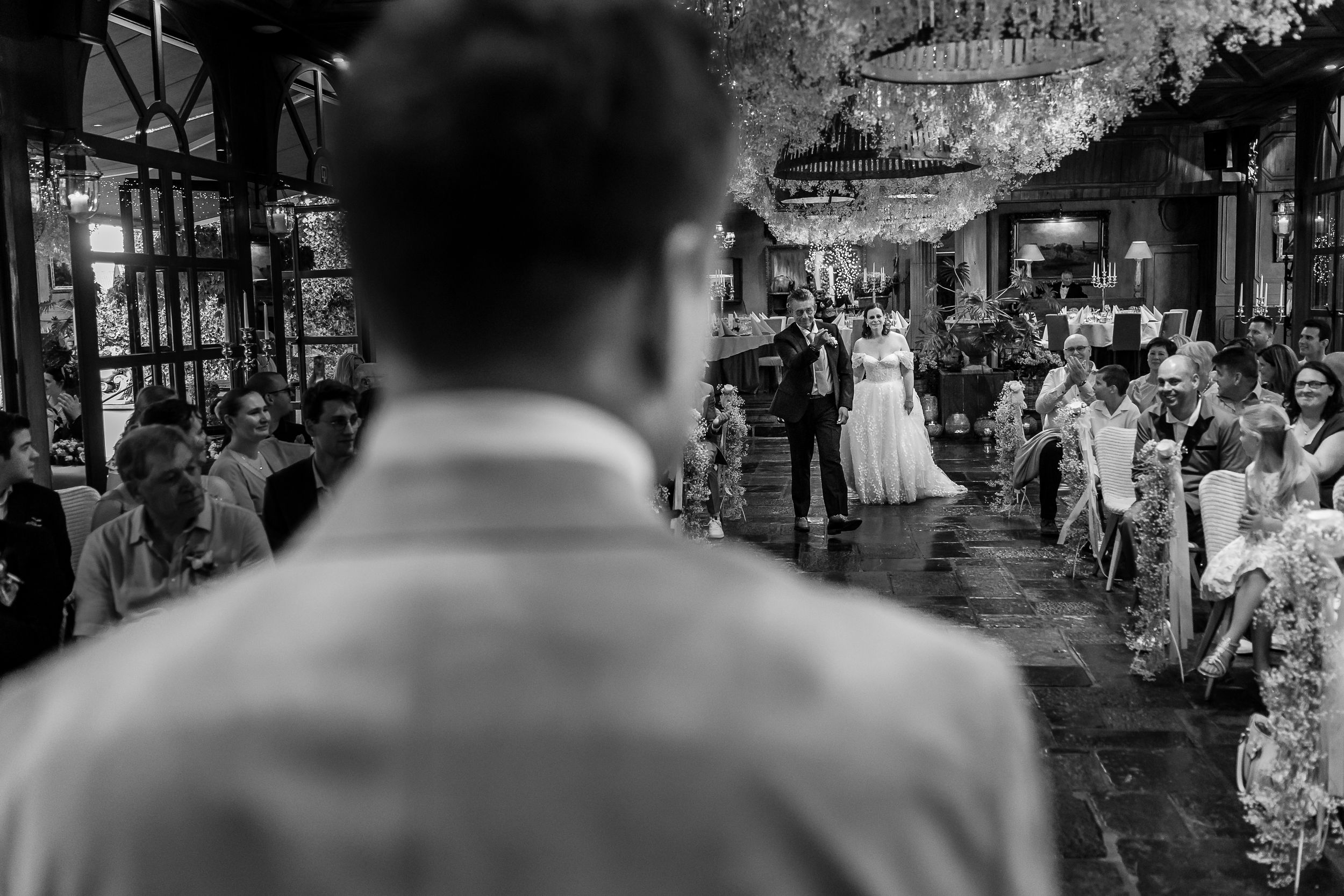 A black and white wedding reception scene shows guests mingling and dancing in an elegant venue.