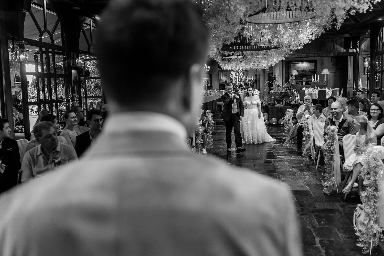 A black and white wedding reception scene shows guests mingling and dancing in an elegant venue.