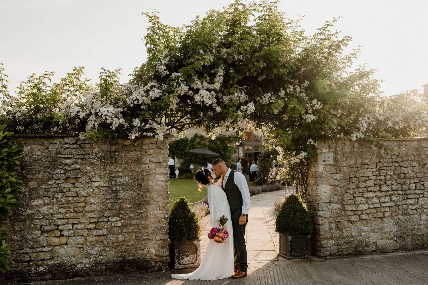 Wedding ceremony setup in rustic wooden barn with white floral arrangements and natural lighting.