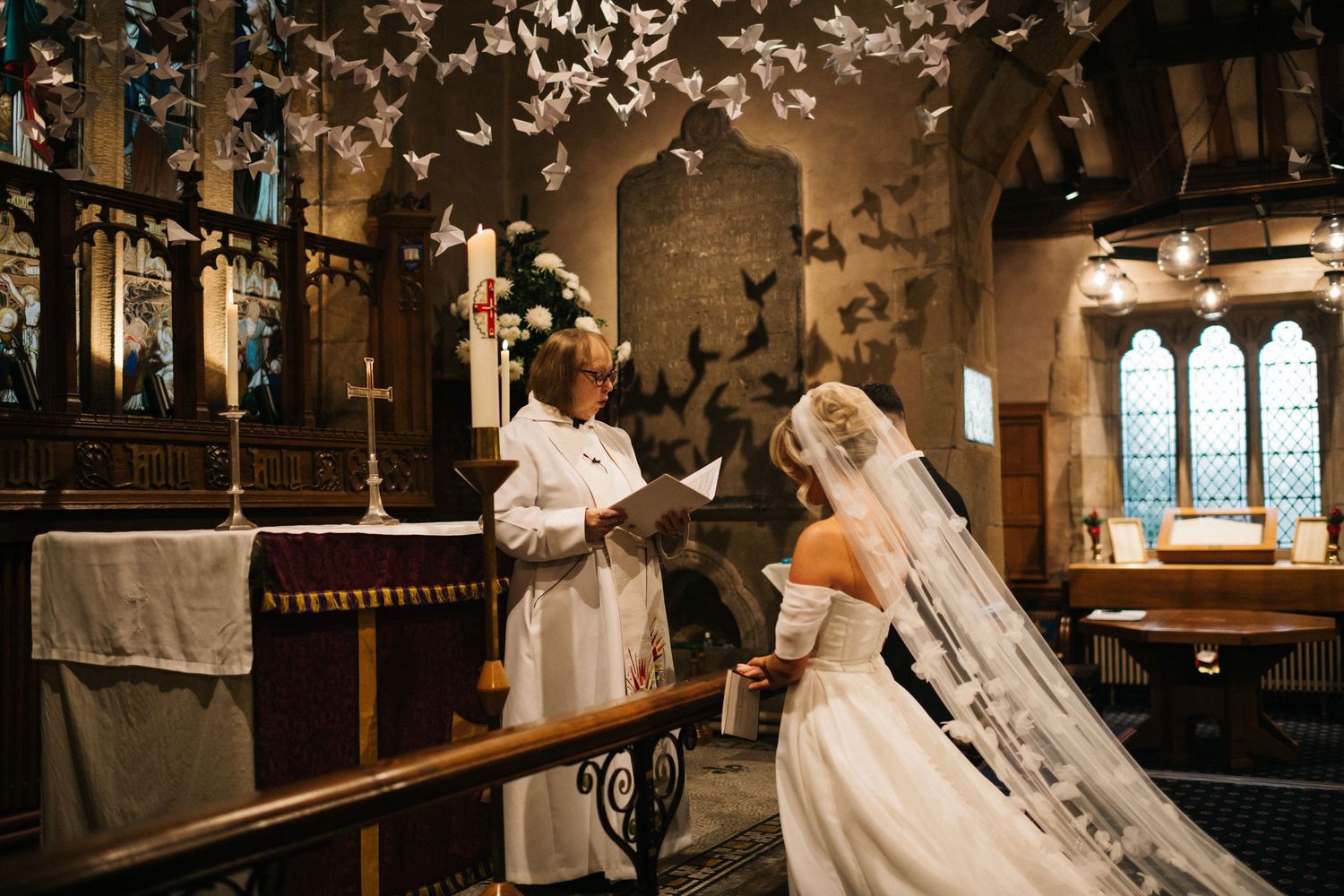 A magical wedding ceremony scene in a historic church with white butterflies floating through the air.