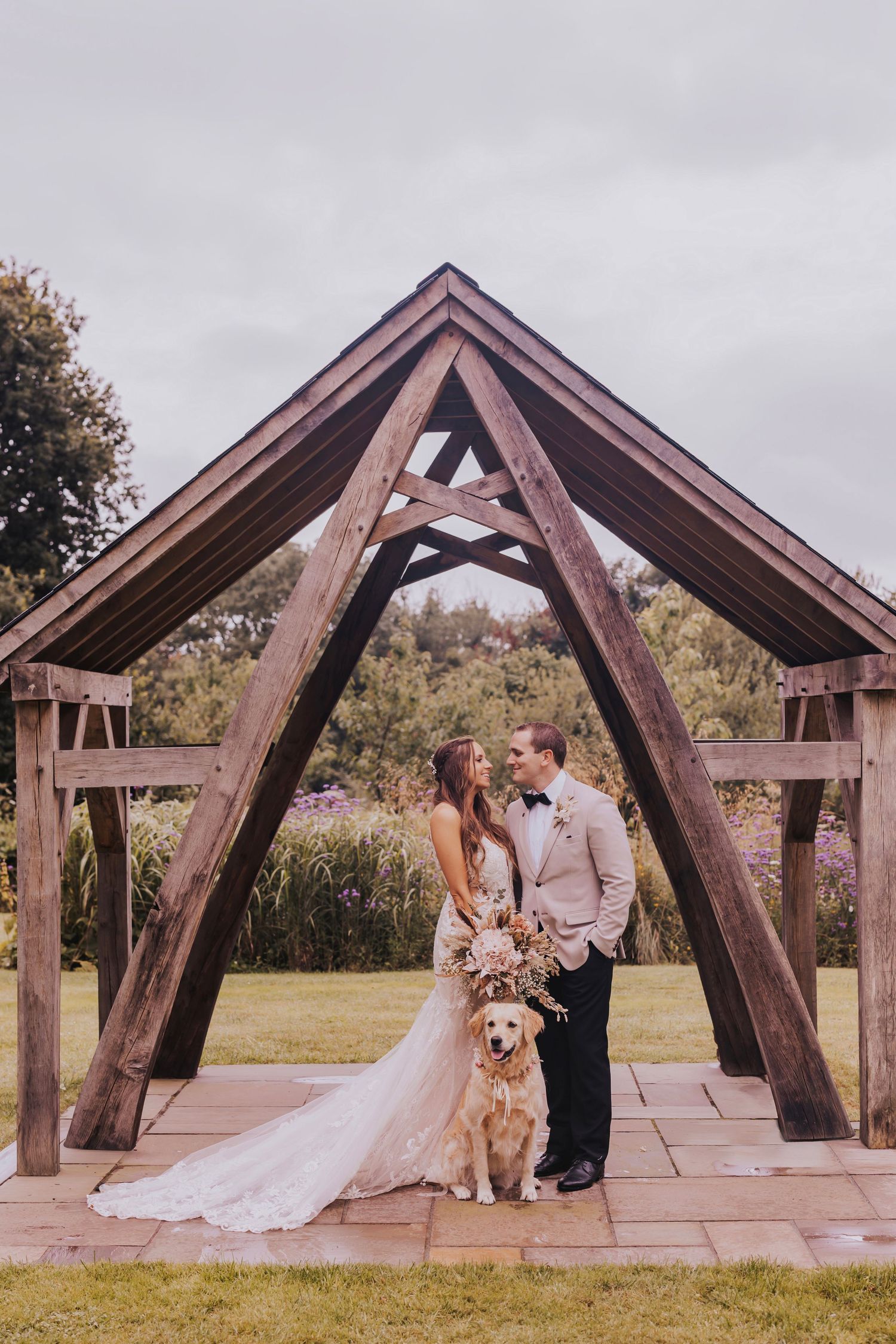 A romantic wedding photo sequence showing a couple and their dog posing under a wooden A-frame archway in a park setting.