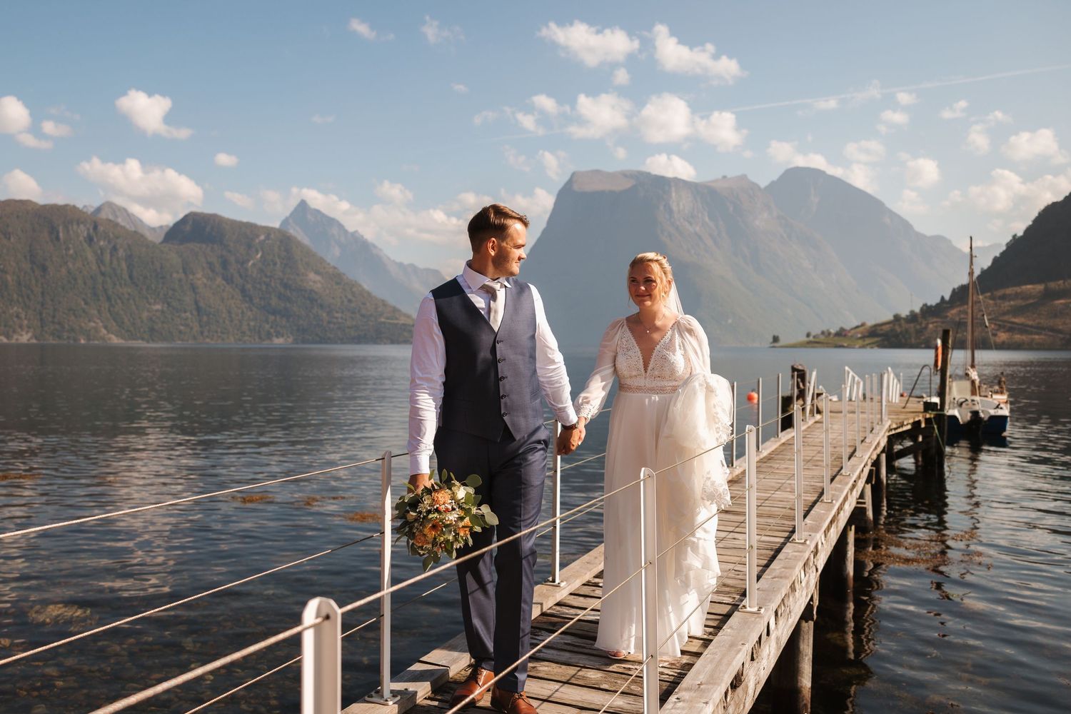 A wedding couple walks along scenic mountain paths in multiple candid shots with dramatic alpine peaks in the background.