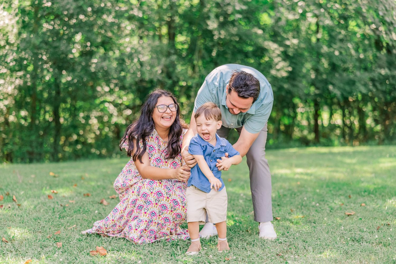 A joyful family moment captured outdoors in a sunny green park setting.