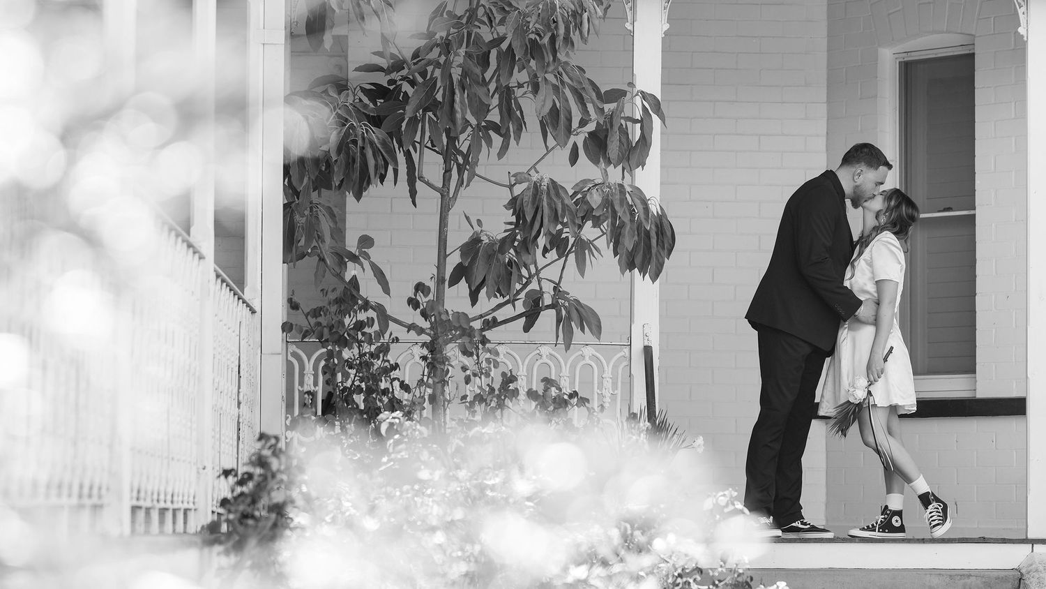 A black and white image of a Bride and Groom sharing a kiss on the old veranda at Kimo Estate, Gundagai Wedding Venue