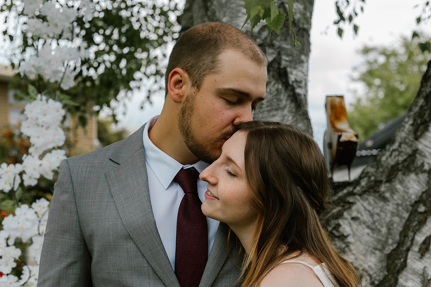 A romantic couple shares intimate moments in a winter forest setting with snow-covered trees in the background.