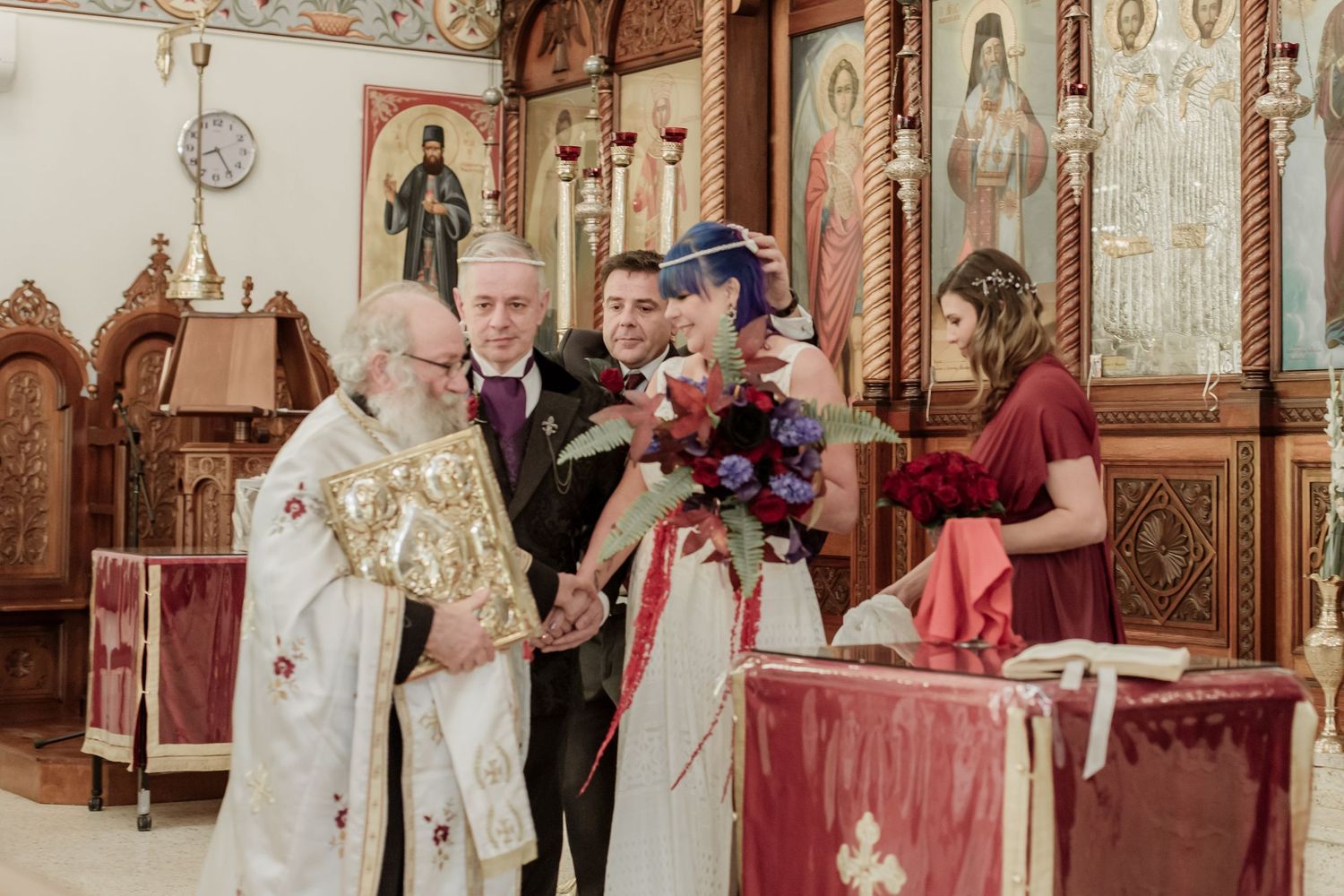 A baptism ceremony takes place in an ornate church with people gathered around a baptismal font.
