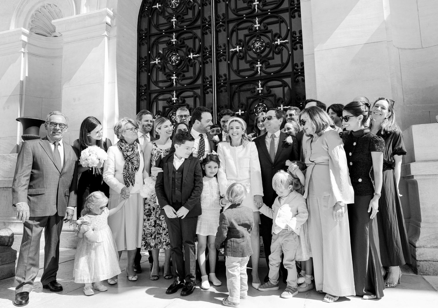 A black and white panoramic photo shows a wedding party lined up outside a church entrance.
