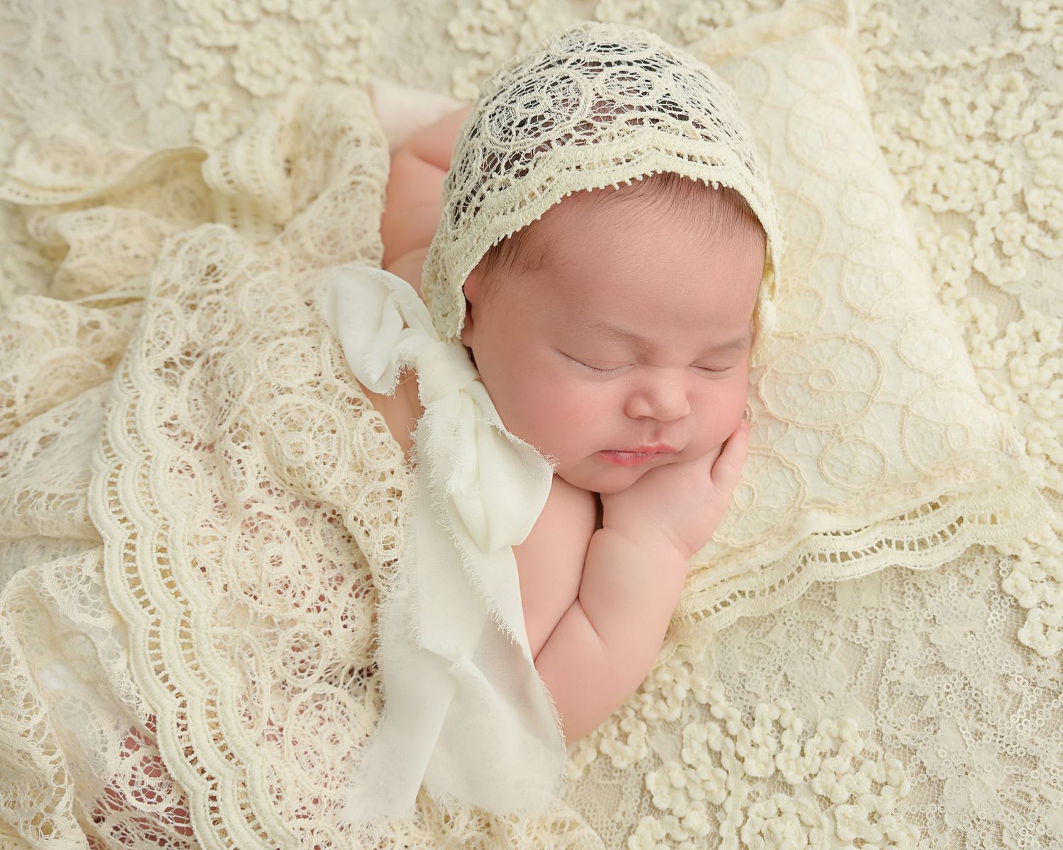 Newborn baby wrapped in soft ivory lace during a Tampa newborn photography session