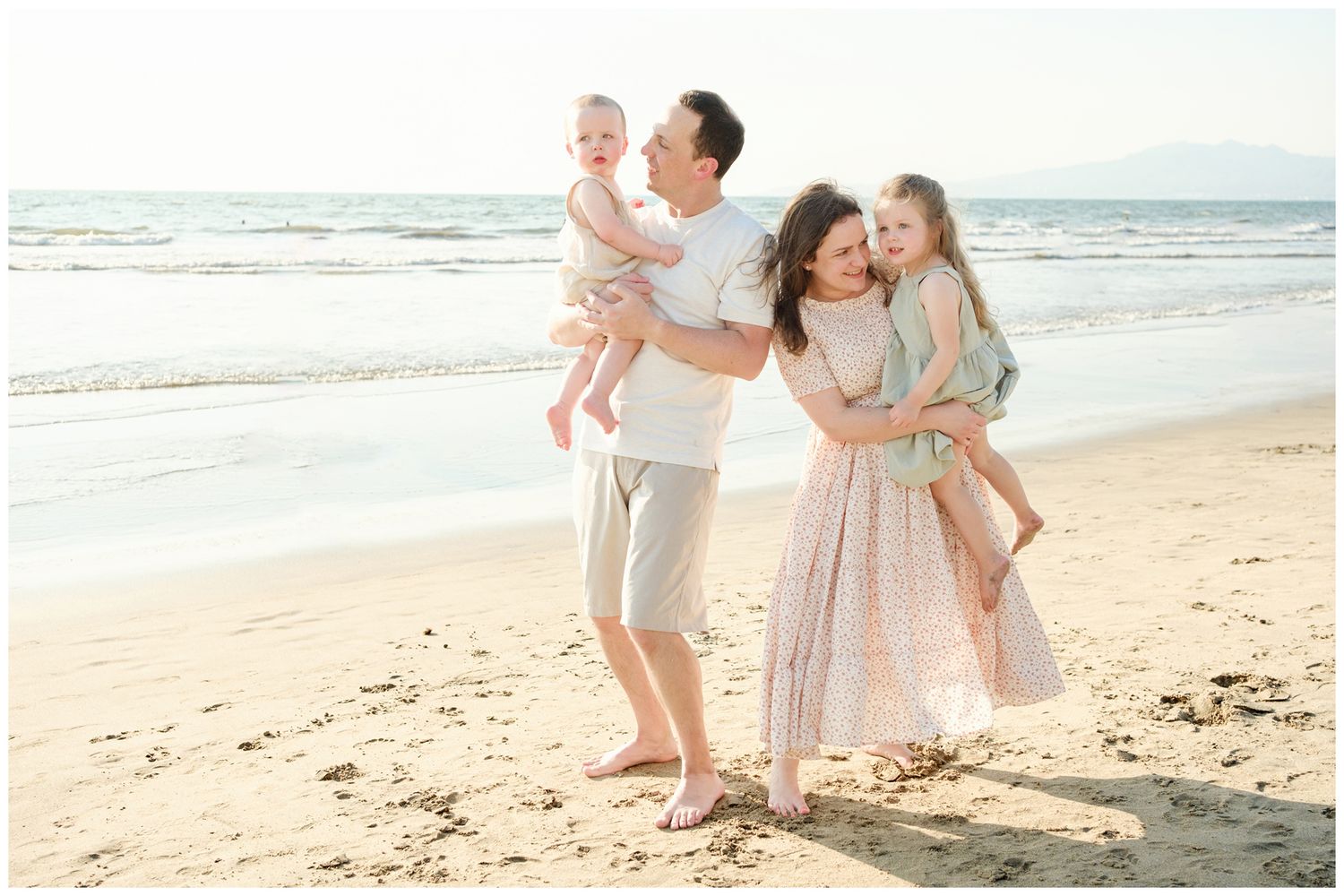 Grand Velas Riviera Nayarit Family Photographer capturing parents embracing their two children during beach family photos.
