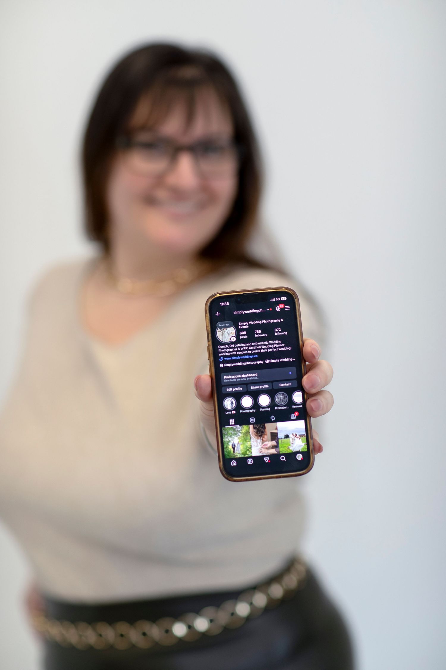 Wedding Planner holding a phone toward the camera showing the social media account for Simply Wedding Events
