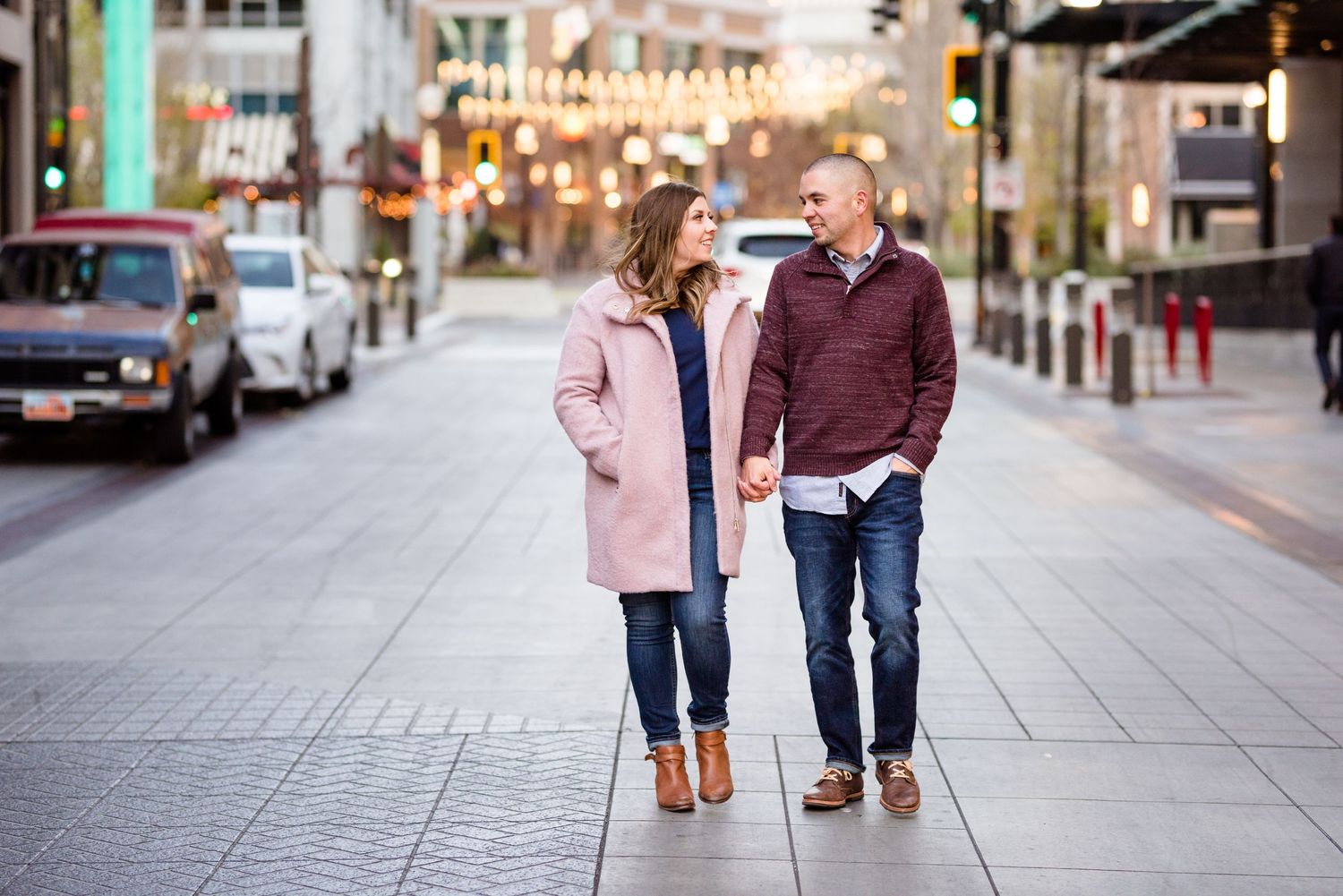 Couple walking hand in hand down a city street during their urban engagement session