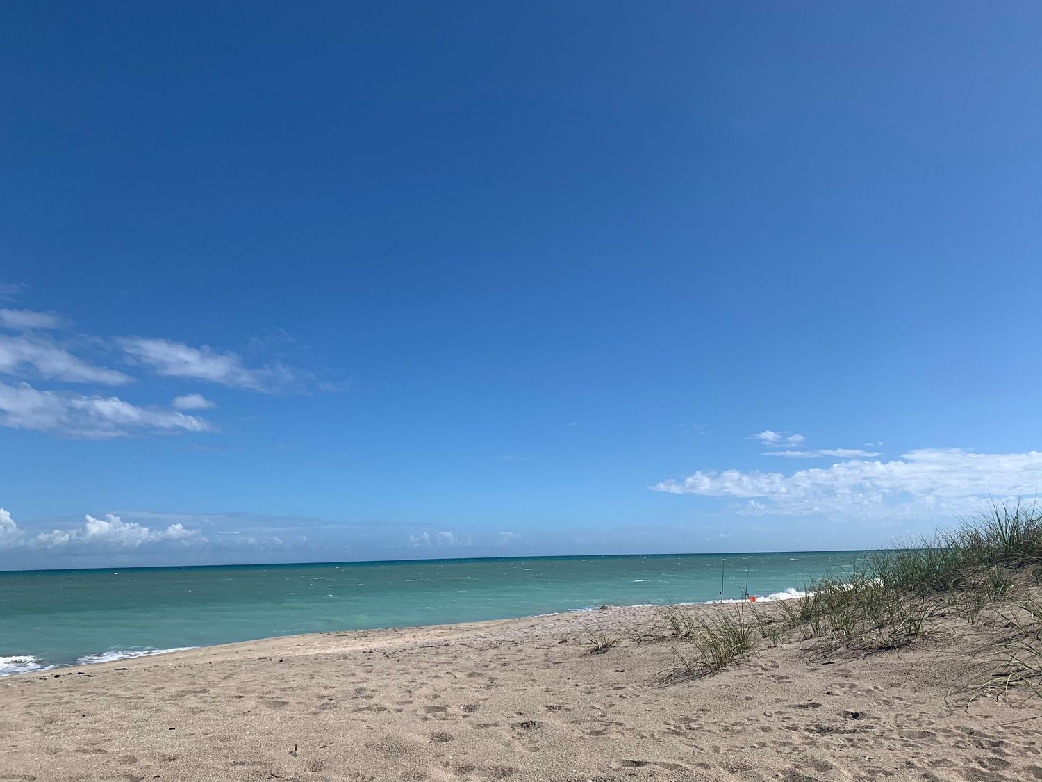 Scenic beach panorama with turquoise waters and white sand stretching along the coastline under blue skies.