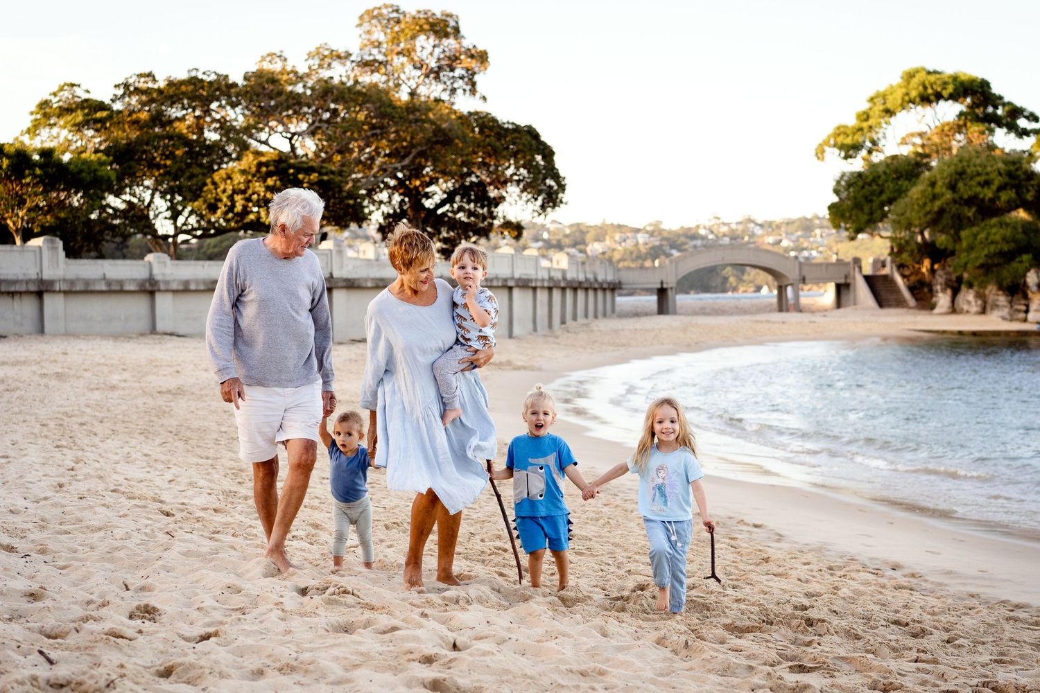 A family walks together along a pristine beach at sunset.