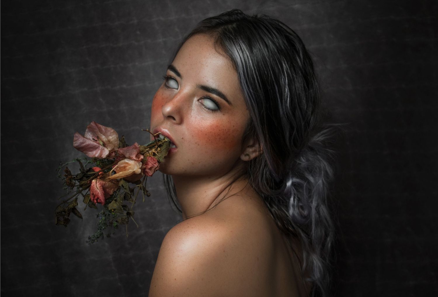 Dark and moody portrait featuring roses and soft lighting in a dramatic composition.