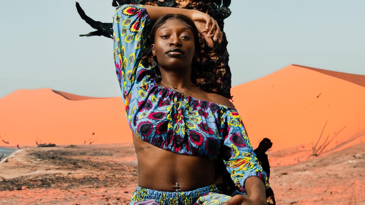 Colorful desert photoshoot with vibrant orange sand dunes in background.