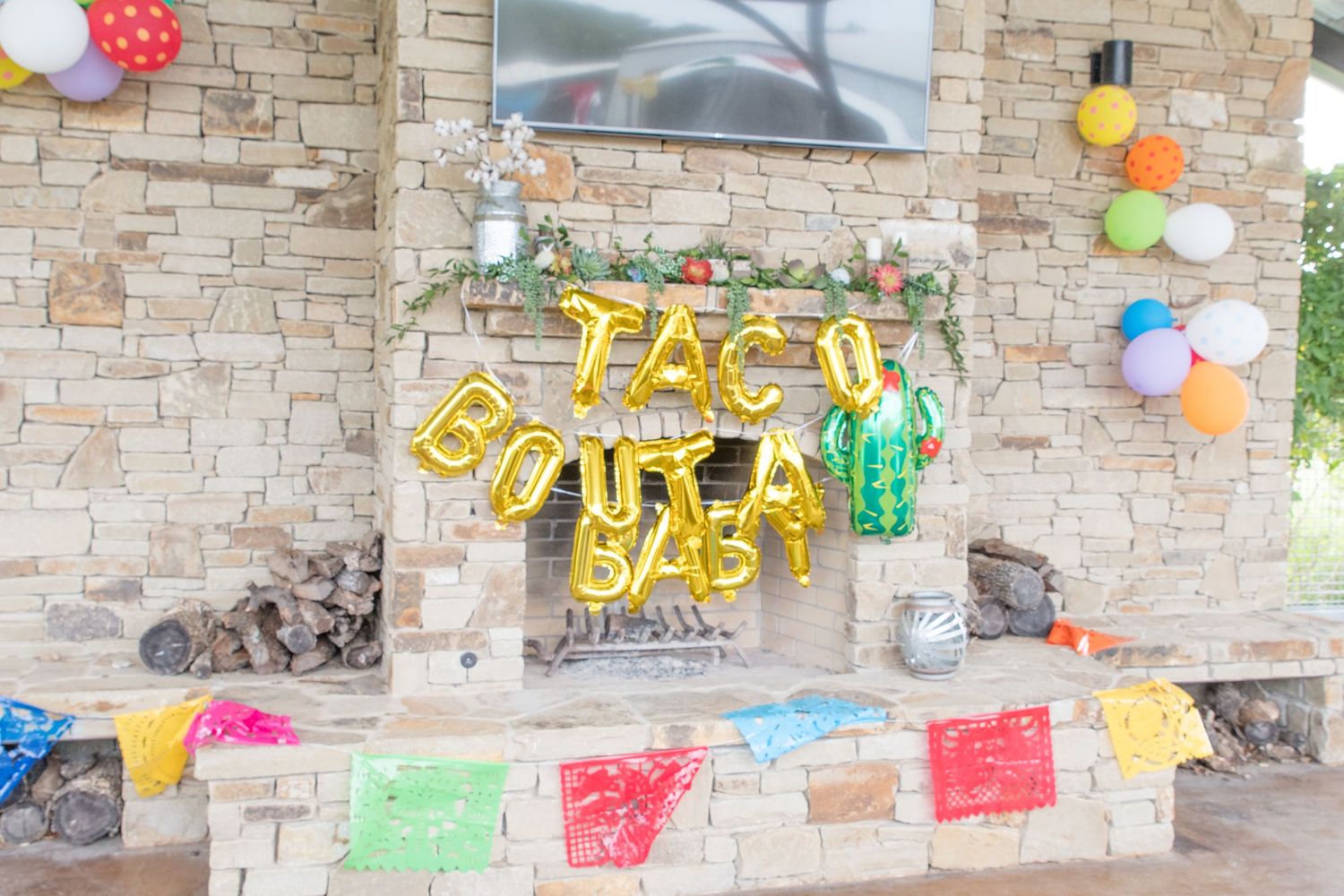 Decorated stone fireplace with yellow letter balloons and colorful party decorations.