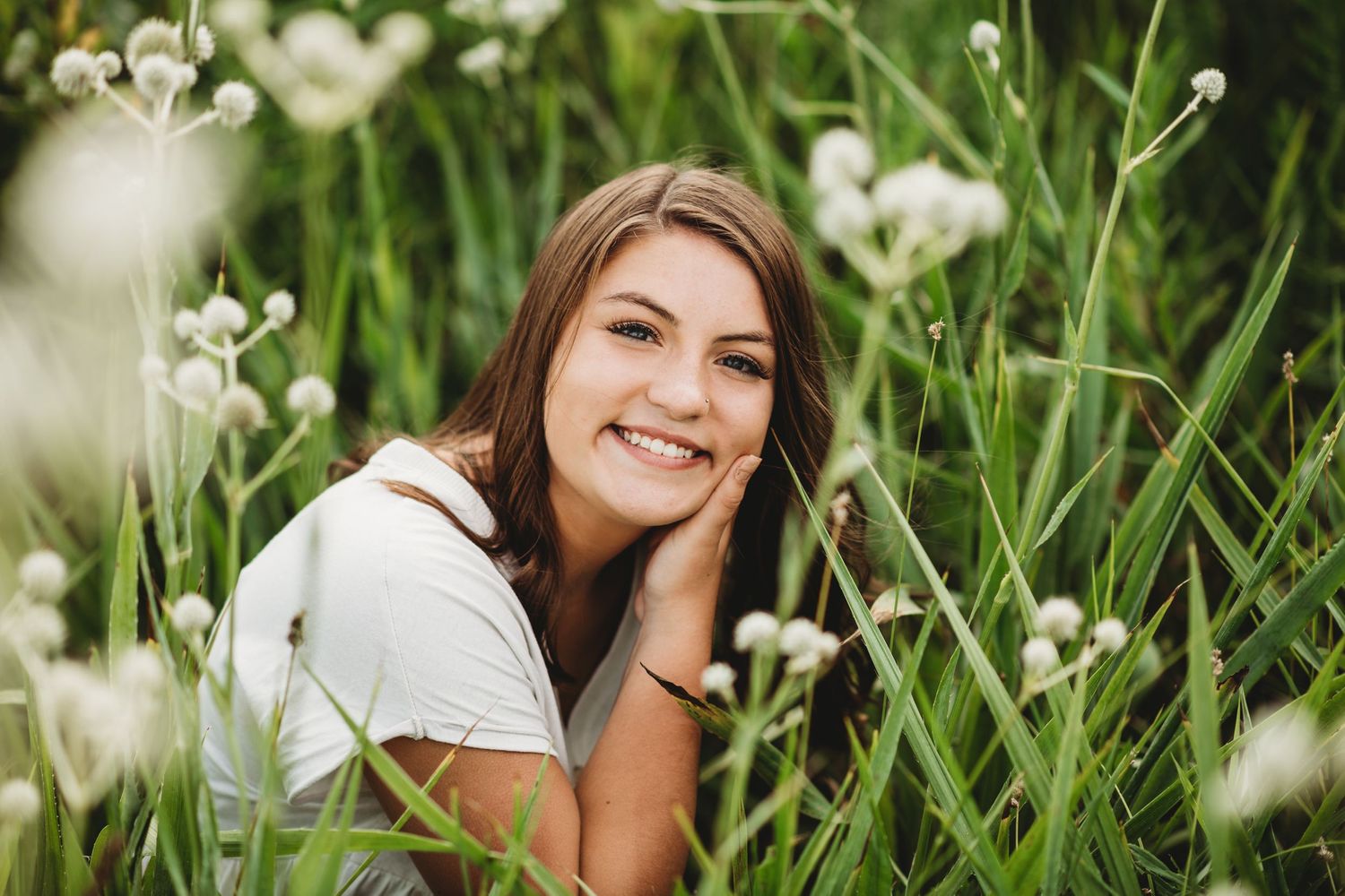 A portrait in a field of white wildflowers with soft natural lighting.