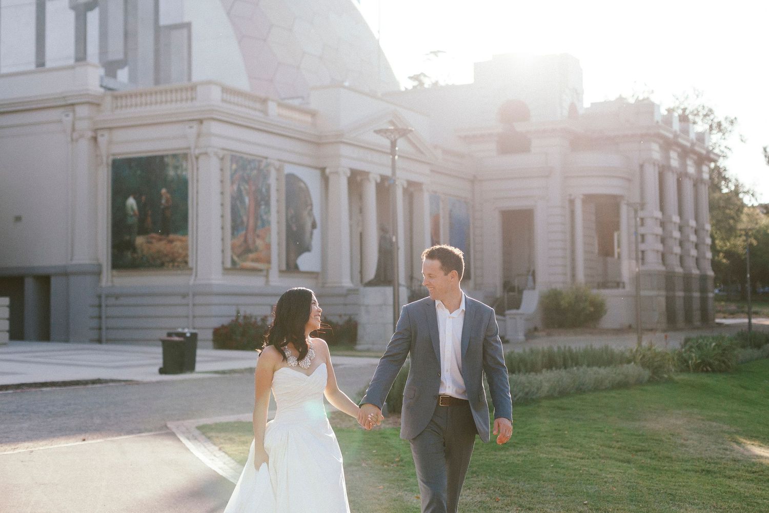 A romantic stroll in front of an elegant white building with columns at golden hour.