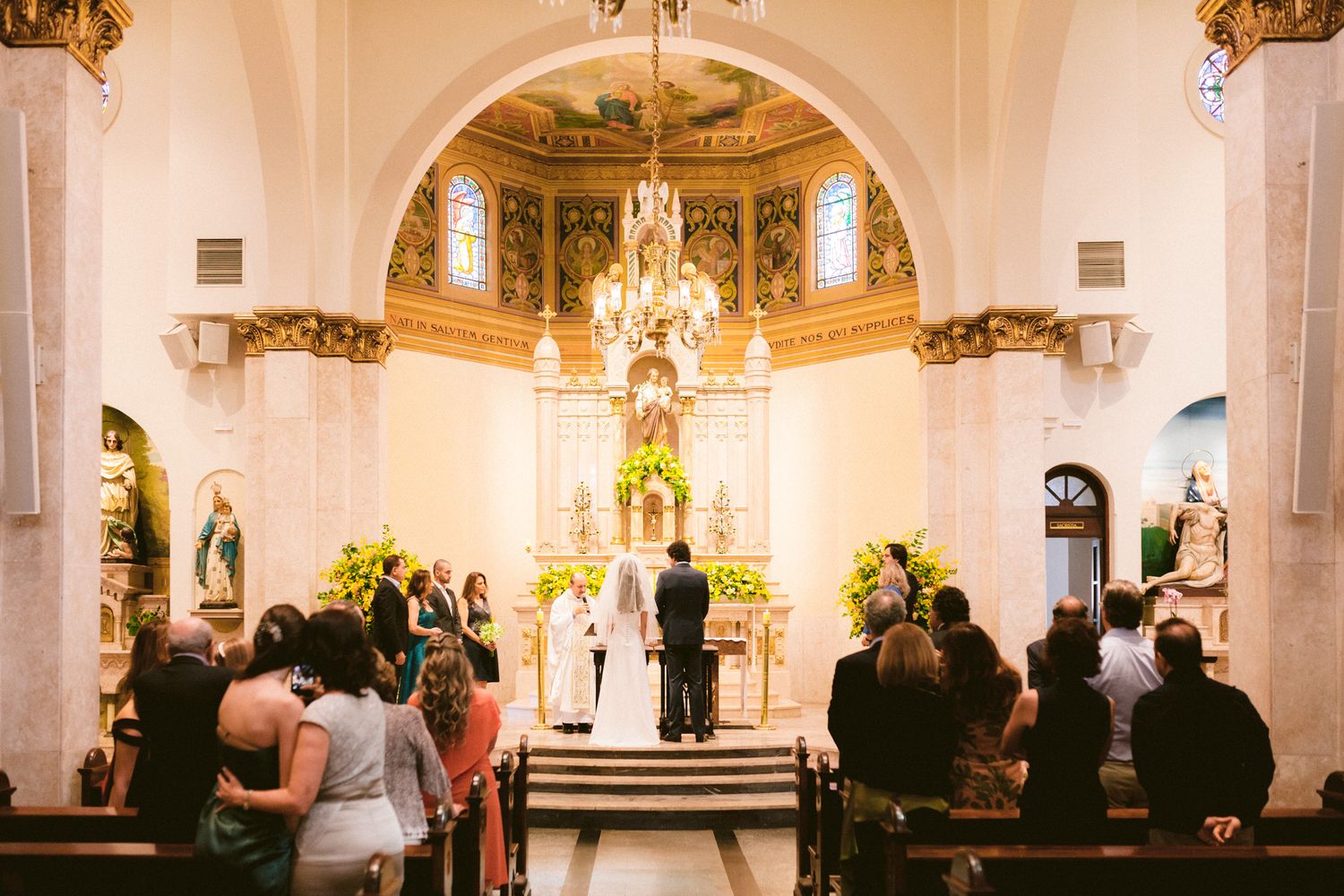 Traditional church wedding ceremony with ornate altar and golden chandelier.