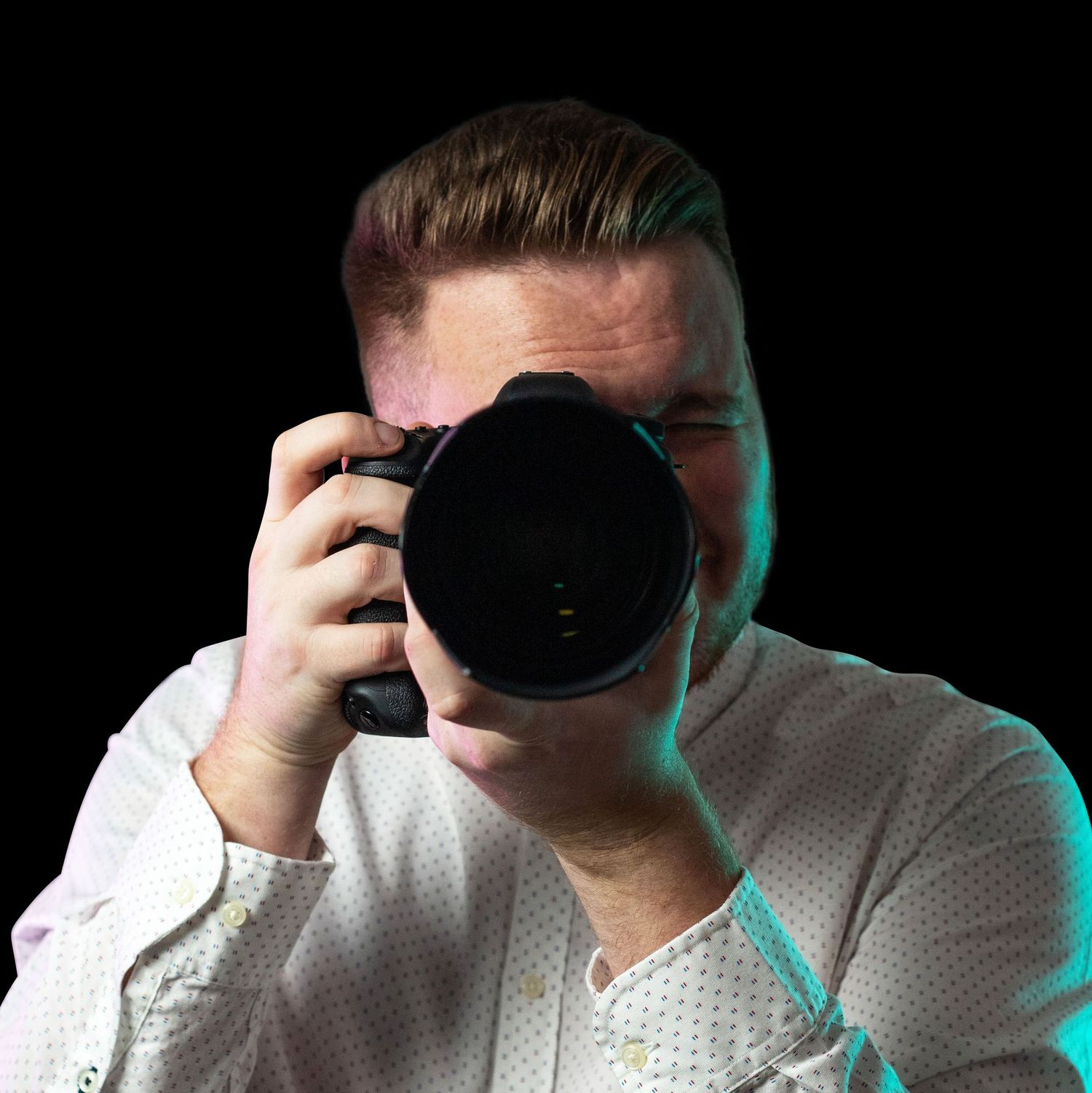 A close-up shot of a photographer holding a camera with dramatic lighting.