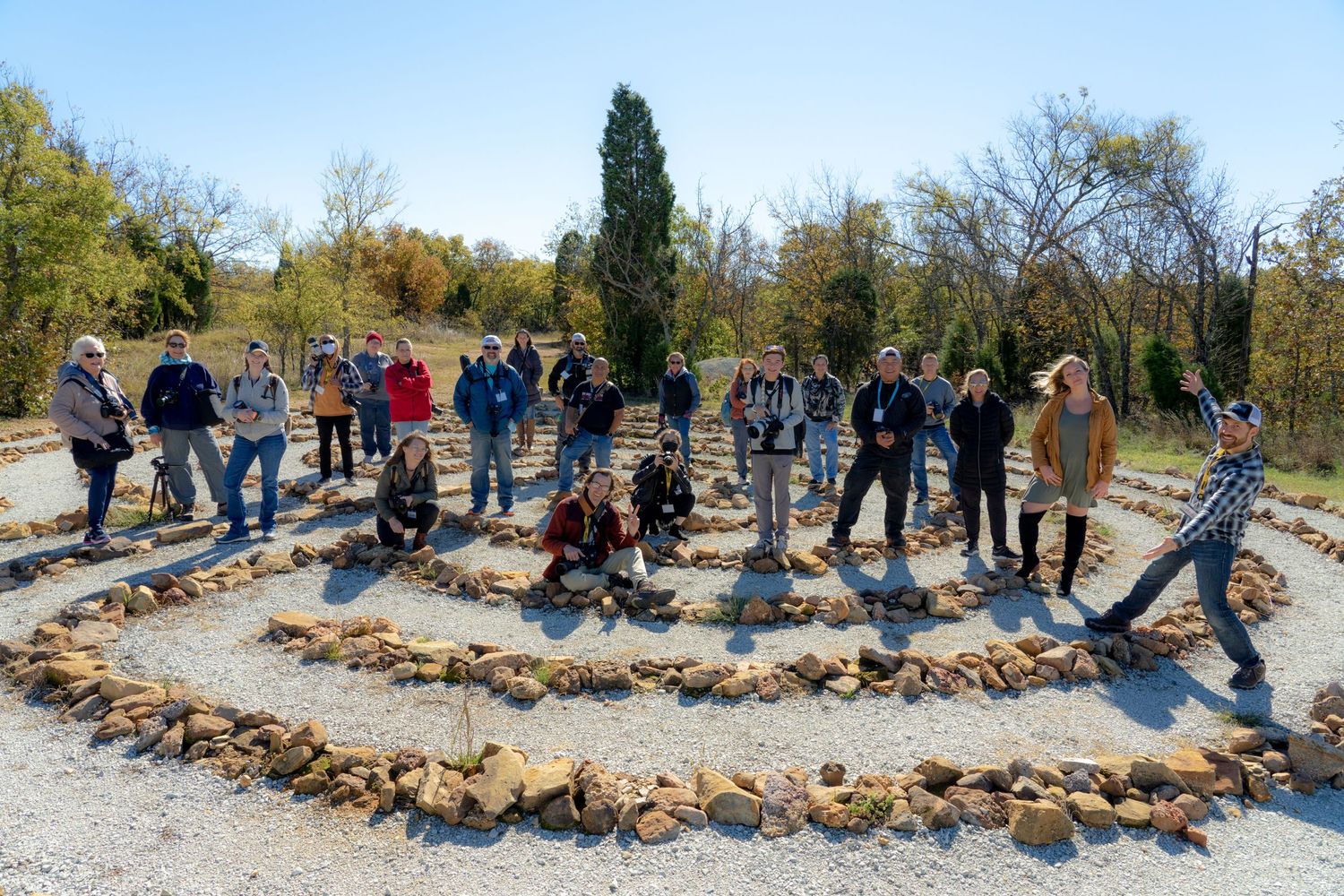 Spiral circle of large  rocks creates an ovular path with gravel in between.. A crowd of photographers poses with smiles