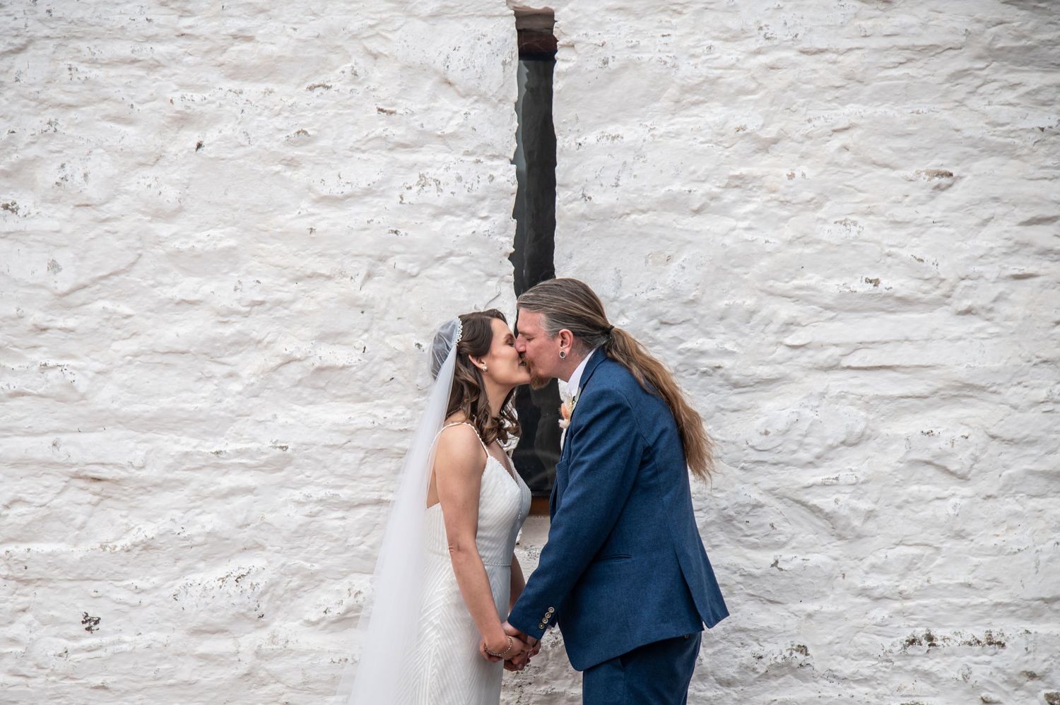 Artistic wedding photography sequence against white stone wall captures romantic moments.