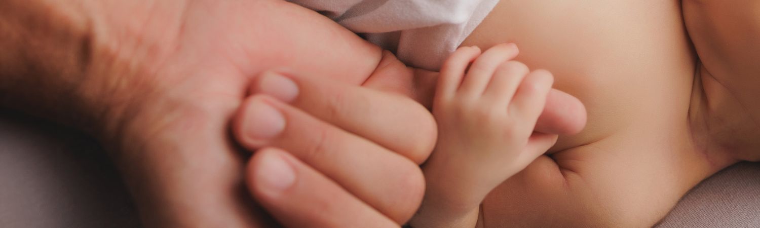 Photo de la main d'un nouveau né tenant le doigt de son papa, en studio à Soissons