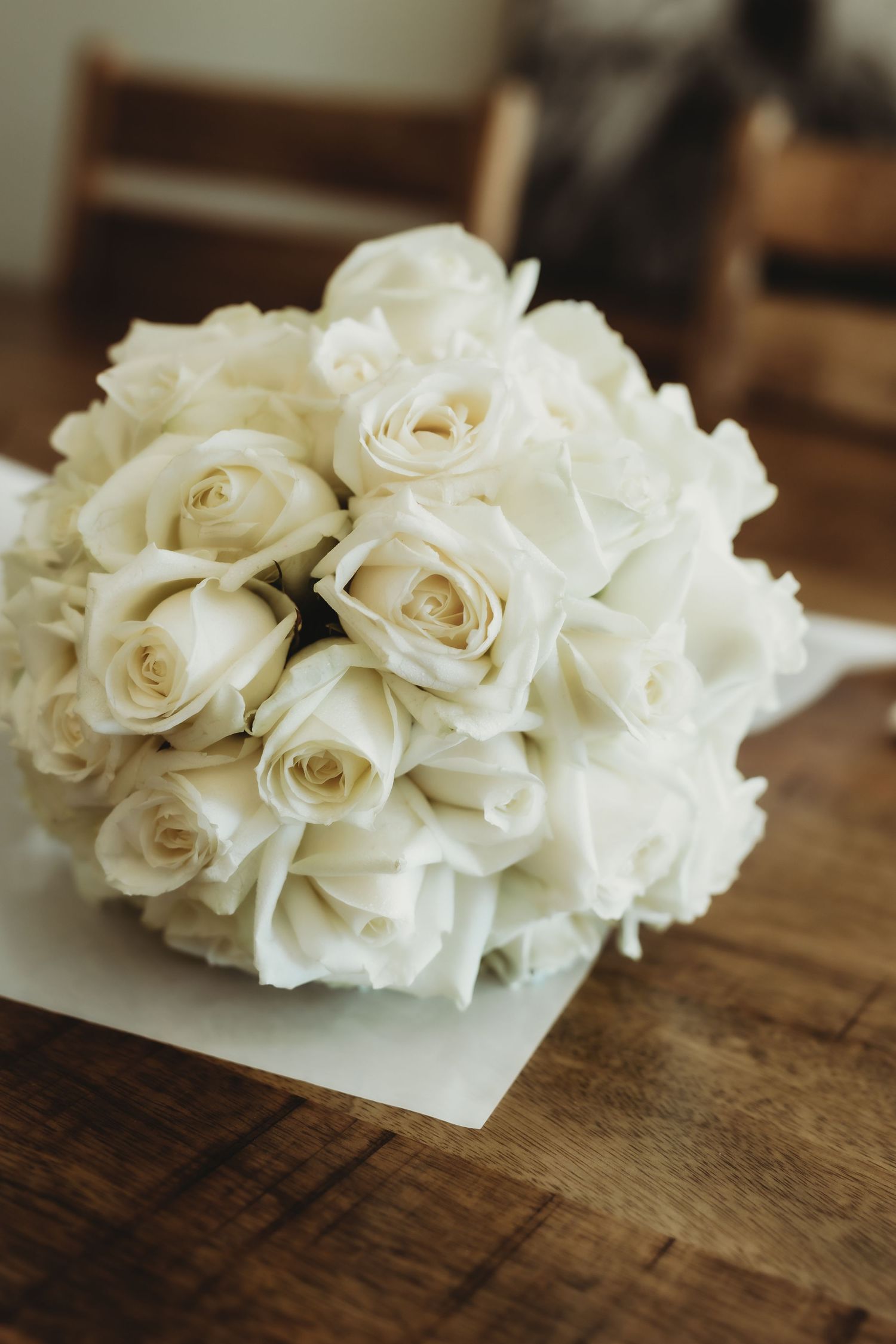White roses and hydrangeas arranged on rustic wooden table surface.