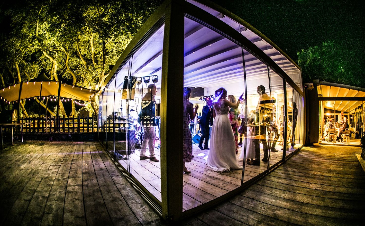 Artistic panoramic sequence of an illuminated walkway with columns and arches at night.