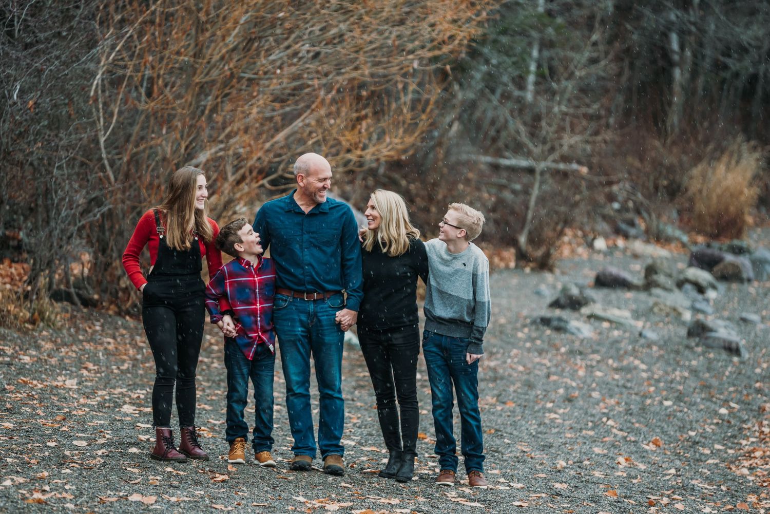 Family group standing together on rocky terrain during fall season.