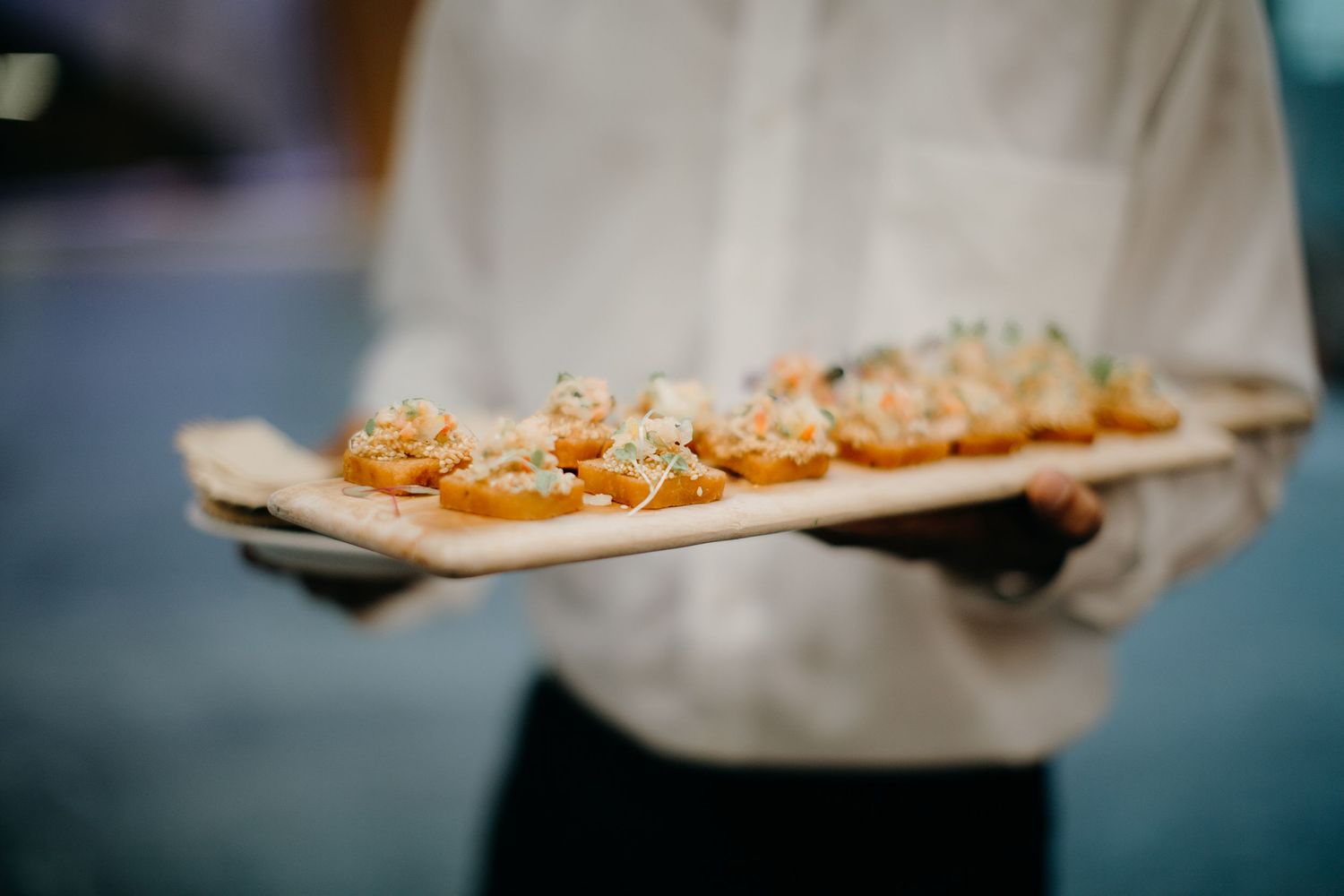waiter holds a platter of canapés