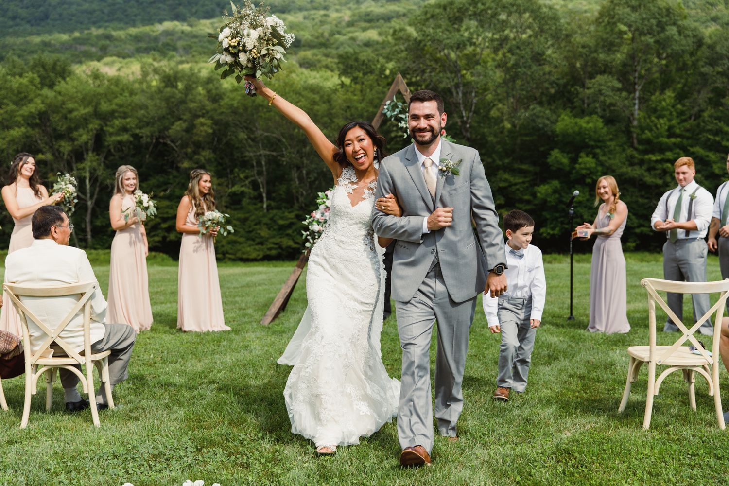 A joyful wedding celebration on a lush green lawn with mountains in the background.