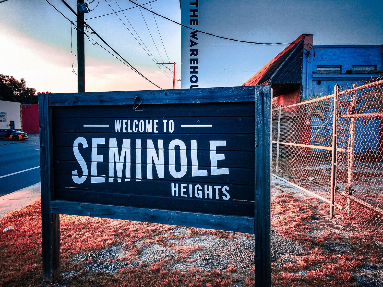 Welcome to Seminole Heights neighborhood sign photographed at dusk with urban background.