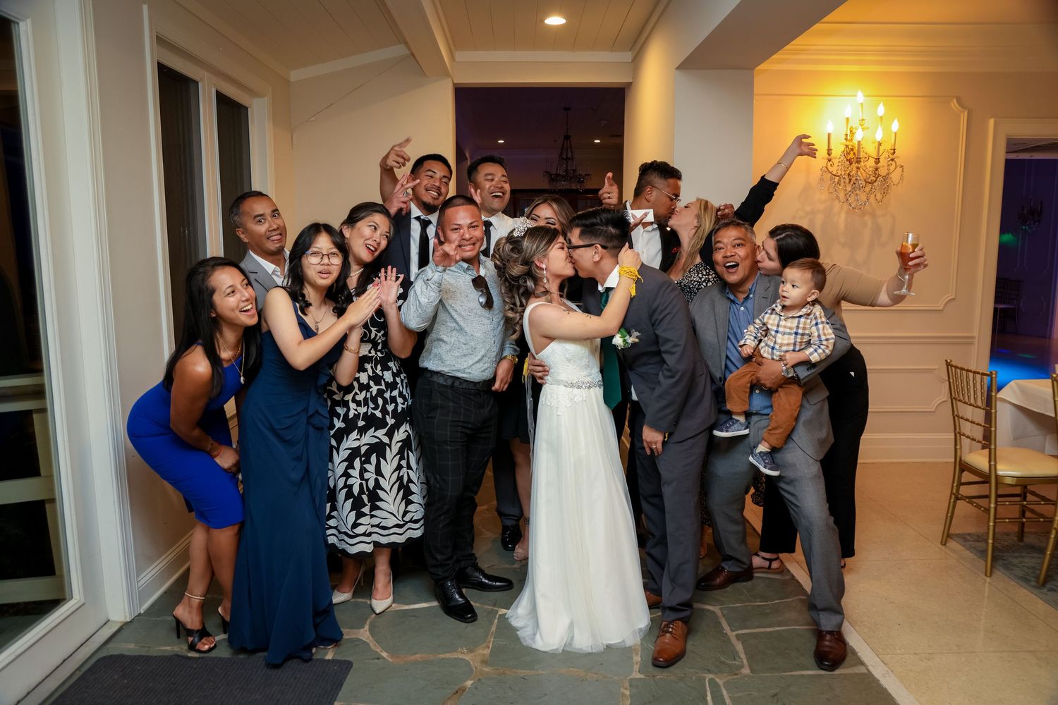 Wedding guests gather for a fun group photo at an indoor reception venue.