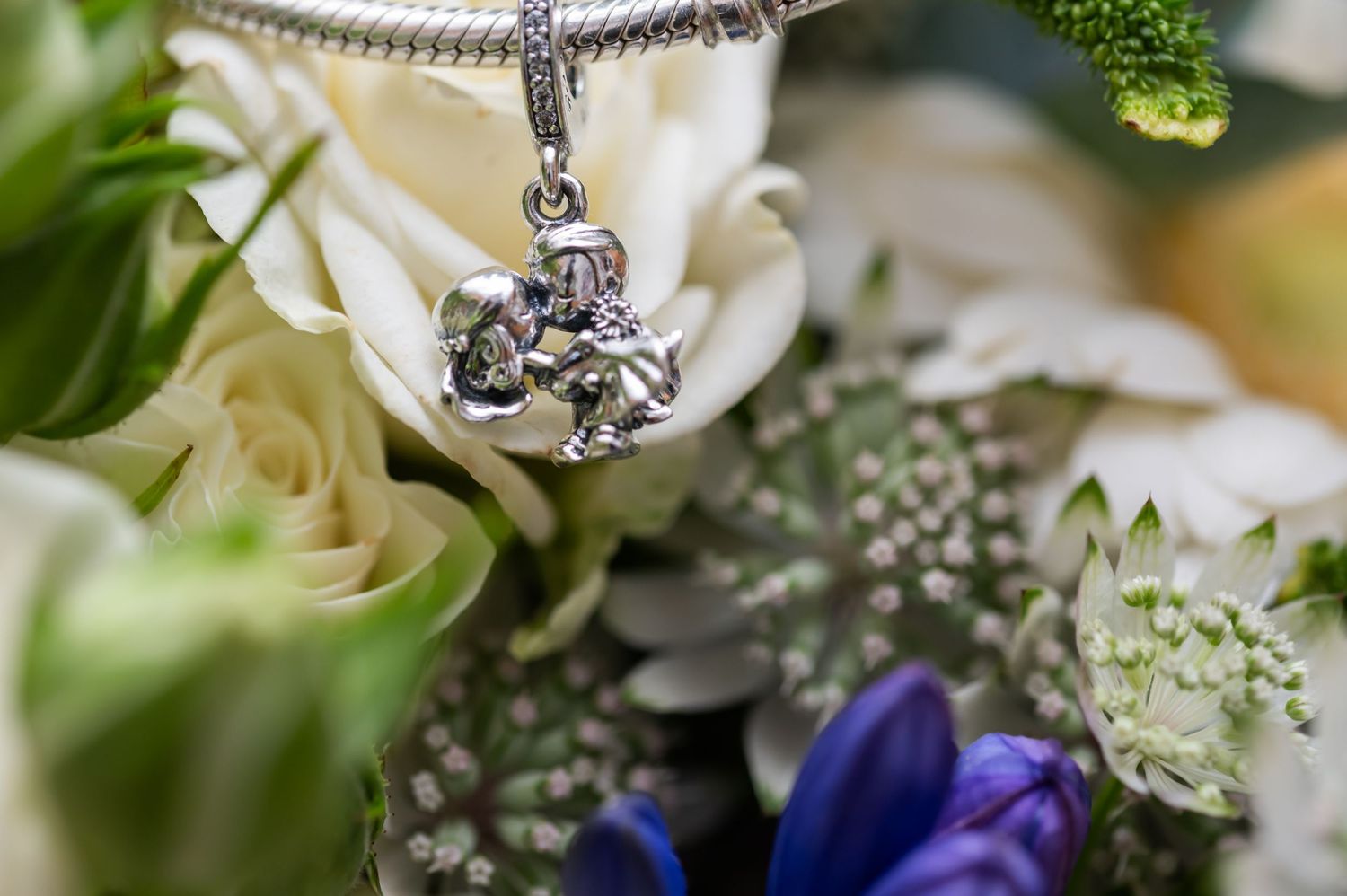 Delicate white roses and purple flowers with silver jewelry accents.