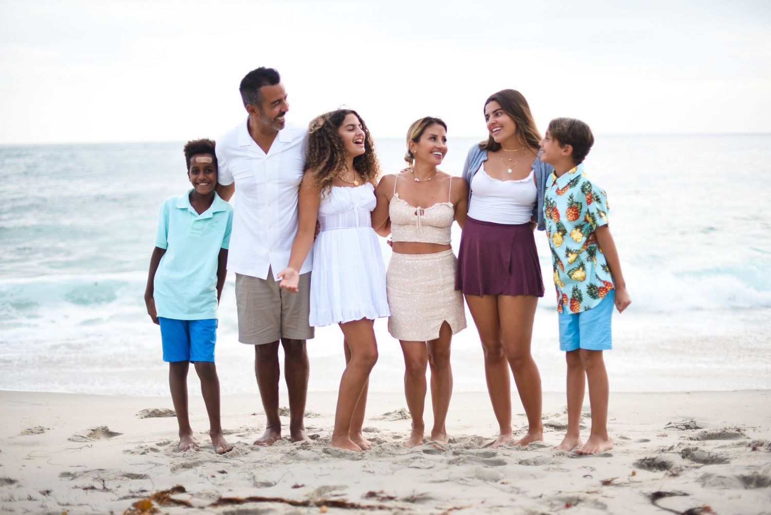 Group of friends in coordinated outfits walking together on a sunny beach.