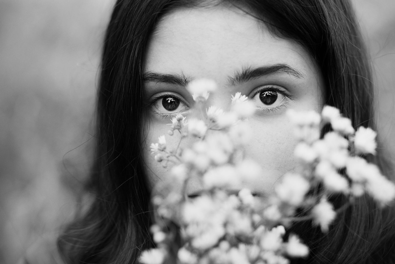 close-up of girl's eyes peering through wildflowers