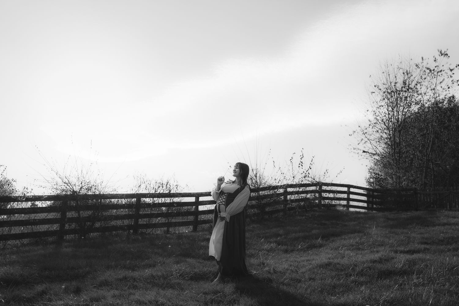 soft photo of a pregnant person with long hair in a field in rural virginia holding a dandelion